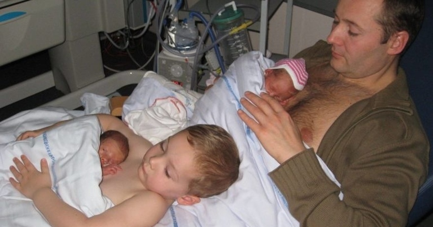 Young boy helps dad to keep his newborn twin siblings warm in viral photo